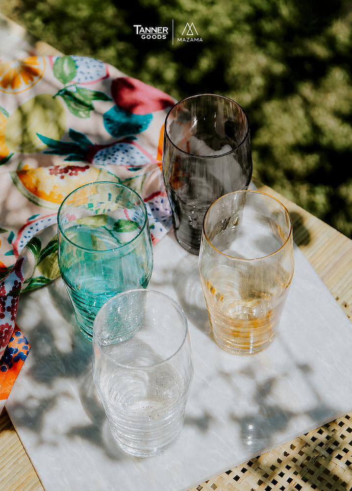 A collection of colorful pint glasses, outdoors in a picnic setting