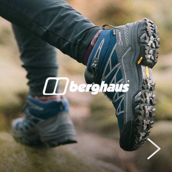 Blue and grey Berghaus hiking shoe on a woodland trail, with the rugged sole prominently displayed to highlight grip and traction.