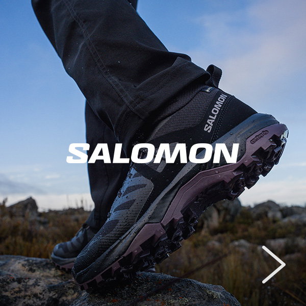 Close-up of a black Salomon hiking shoe stepping onto rocky terrain, highlighting aggressive tread and trail-ready performance features.