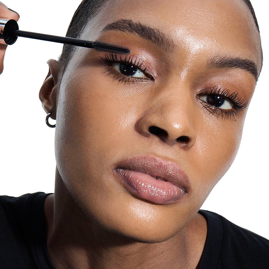 Close-up of a woman with black mascara being carefully applied to her eyelashes.