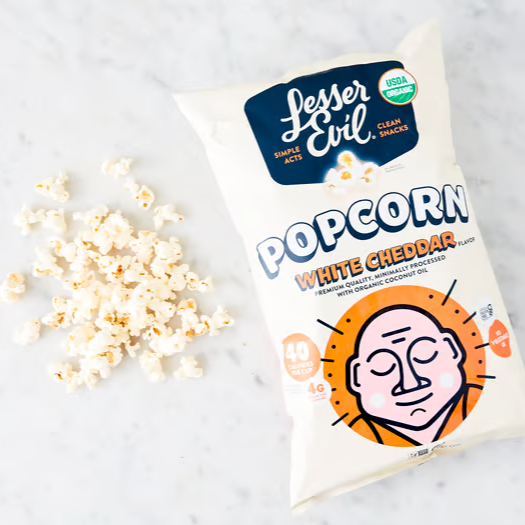 A bag of Lesser Evil organic white cheddar popcorn with popcorn scattered beside it