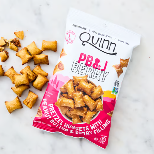 A bag of Quinn PB&J Berry pretzel nuggets with pretzels scattered beside it