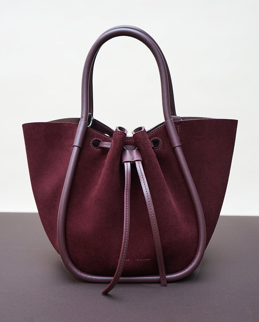 Still life image of Small Ruched Tote in Soft Suede in oxblood on a brown surface
