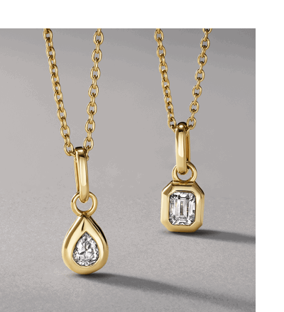 Two yellow gold necklaces featuring bezel-set pear-shaped and emerald-cut diamonds.