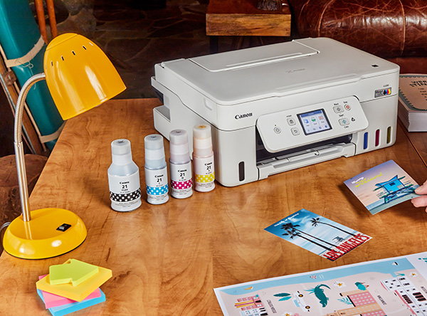 Vibrant Pictures Printed from a Canon Printer, sitting on a desk, alongside Colorful Printer Ink