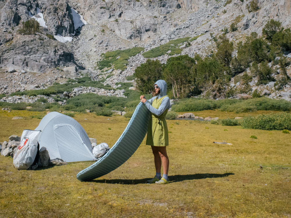 Woman at campsite setting up her sleeping pad.