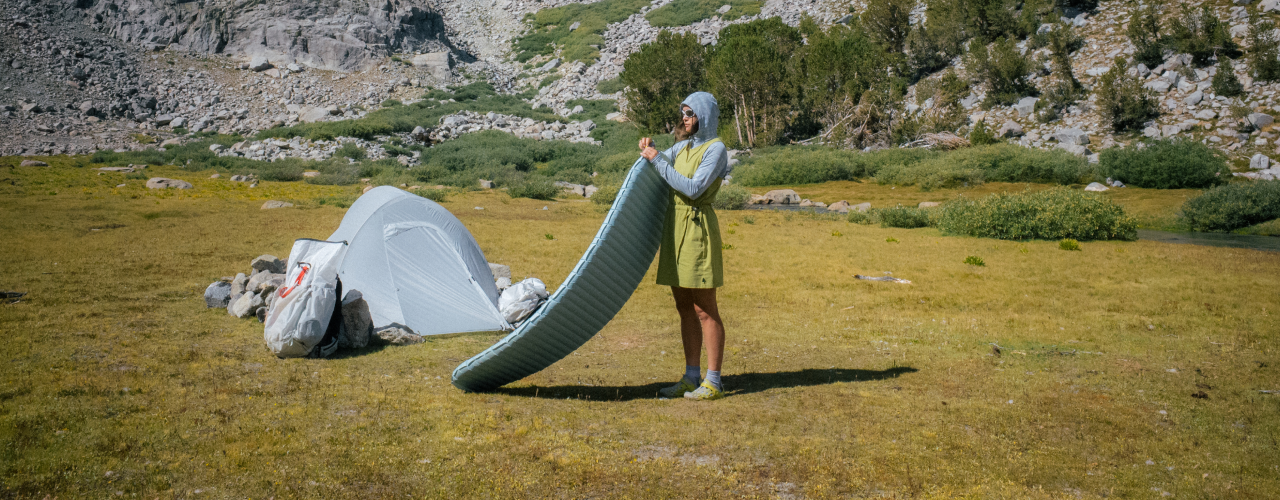 Woman at campsite setting up her sleeping pad.