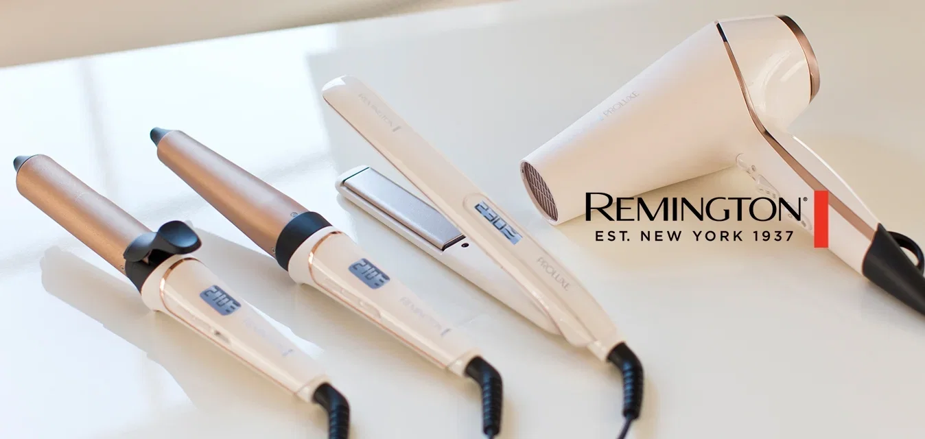 Dos rizadores, una plancha para el cabello y un secador de pelo, todos blancos con detalles dorados, colocados sobre una encimera blanca.