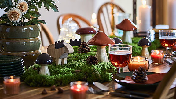 A dining table decorated with pine cones, greenery and the IKEA HÖSTAGILLE mushroom decoration set of 3.