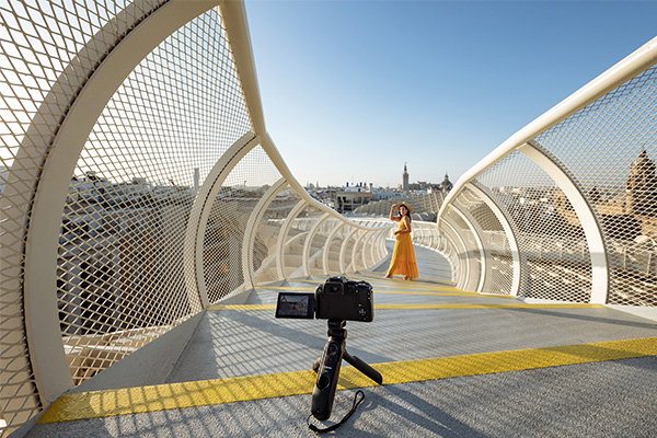 appareil photo sur un trepied et femme qui se filme de loin