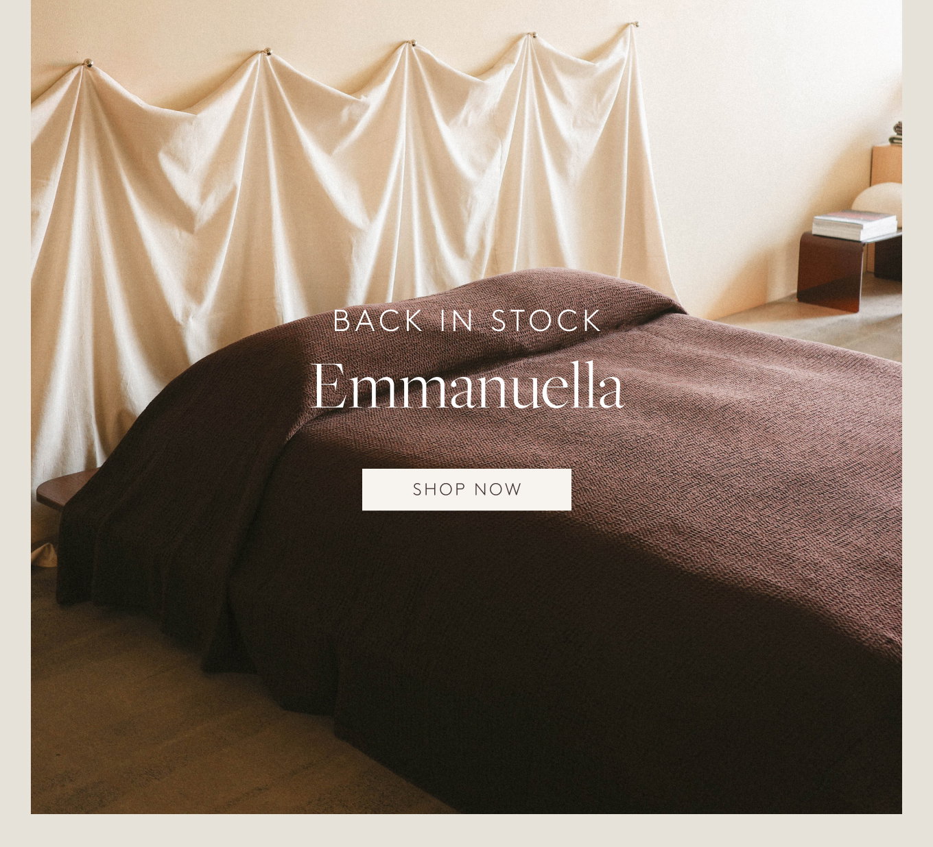 Plum textured blanket covering a bed in a room with a draped fabric headboard