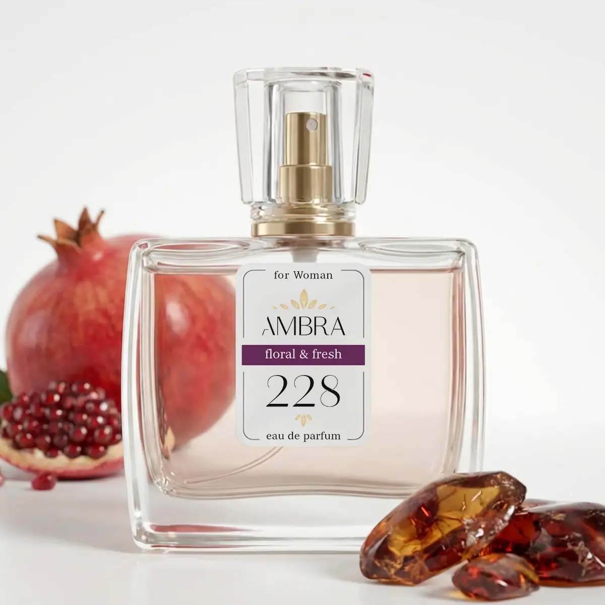 Clear glass bottle of AMBRA 228 floral & fresh eau de parfum for women, with pomegranate and amber stones