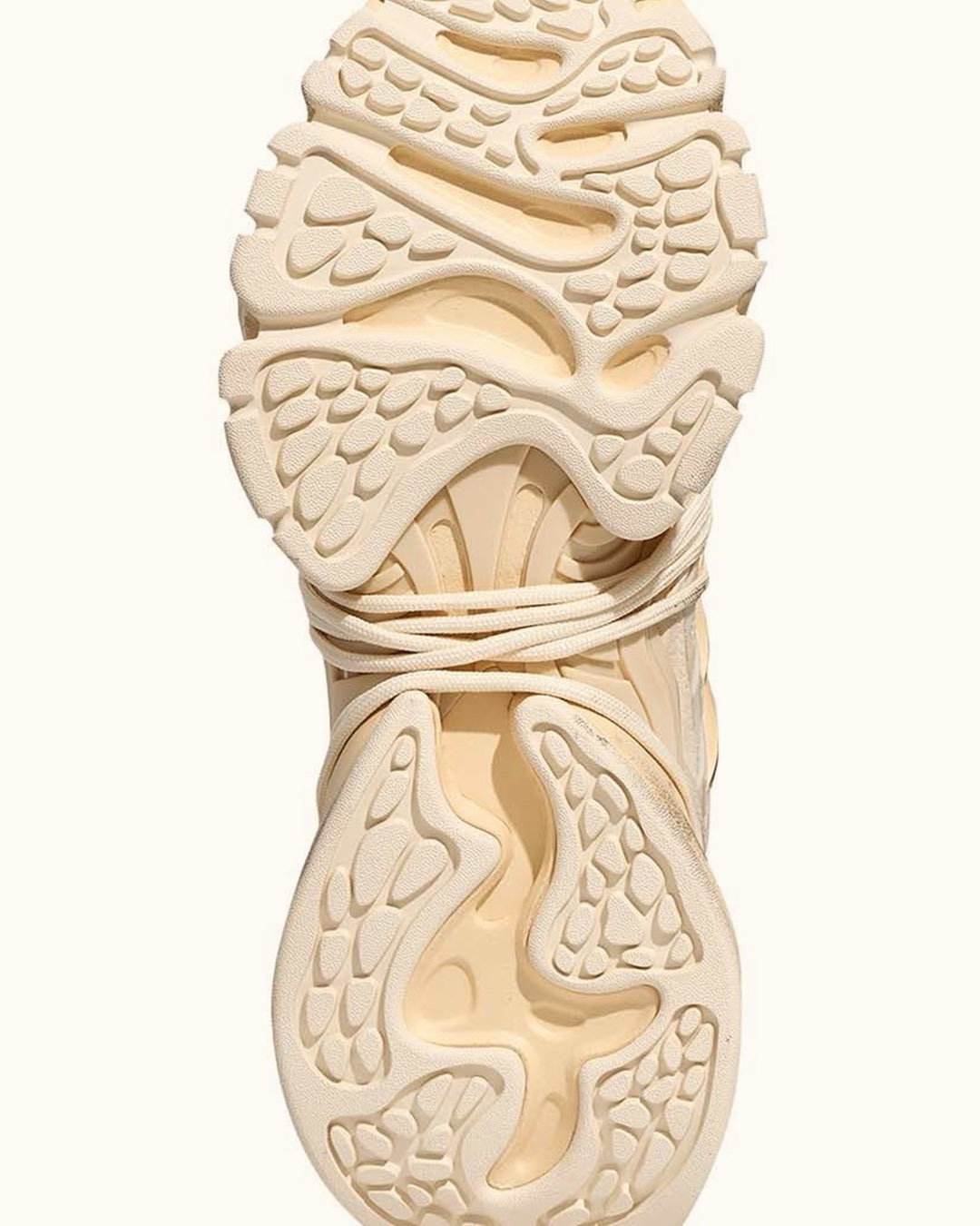 Close-up of beige sneaker sole with wrapped laces, showing textured tread pattern for grip, cushioning and anti-slip performance