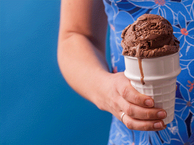Person holding a wafer cone with a scoop of chocolate ice cream