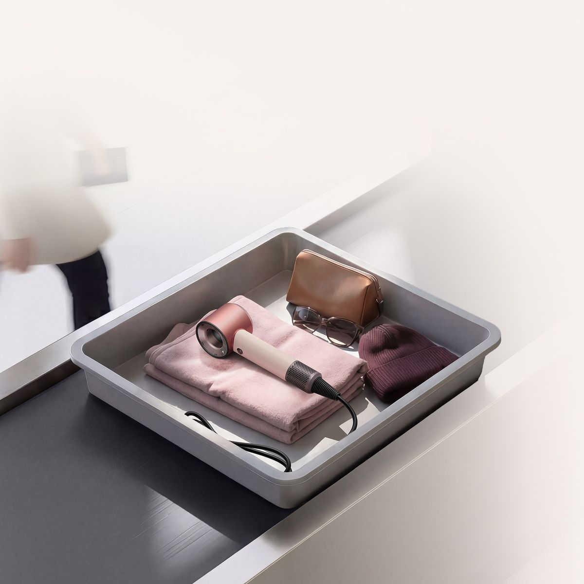 El secador Dyson Supersonic™ Travel en una bandeja de control de seguridad del aeropuerto.
