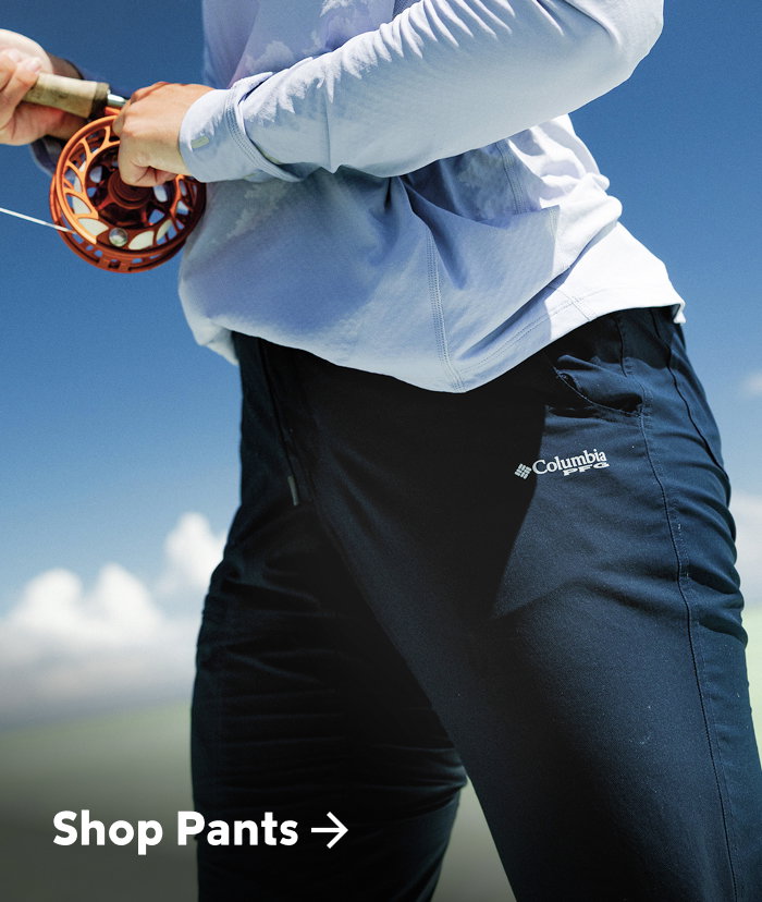 Waist-down image of a woman fishing, wearing navy pants with text: Shop Bottoms