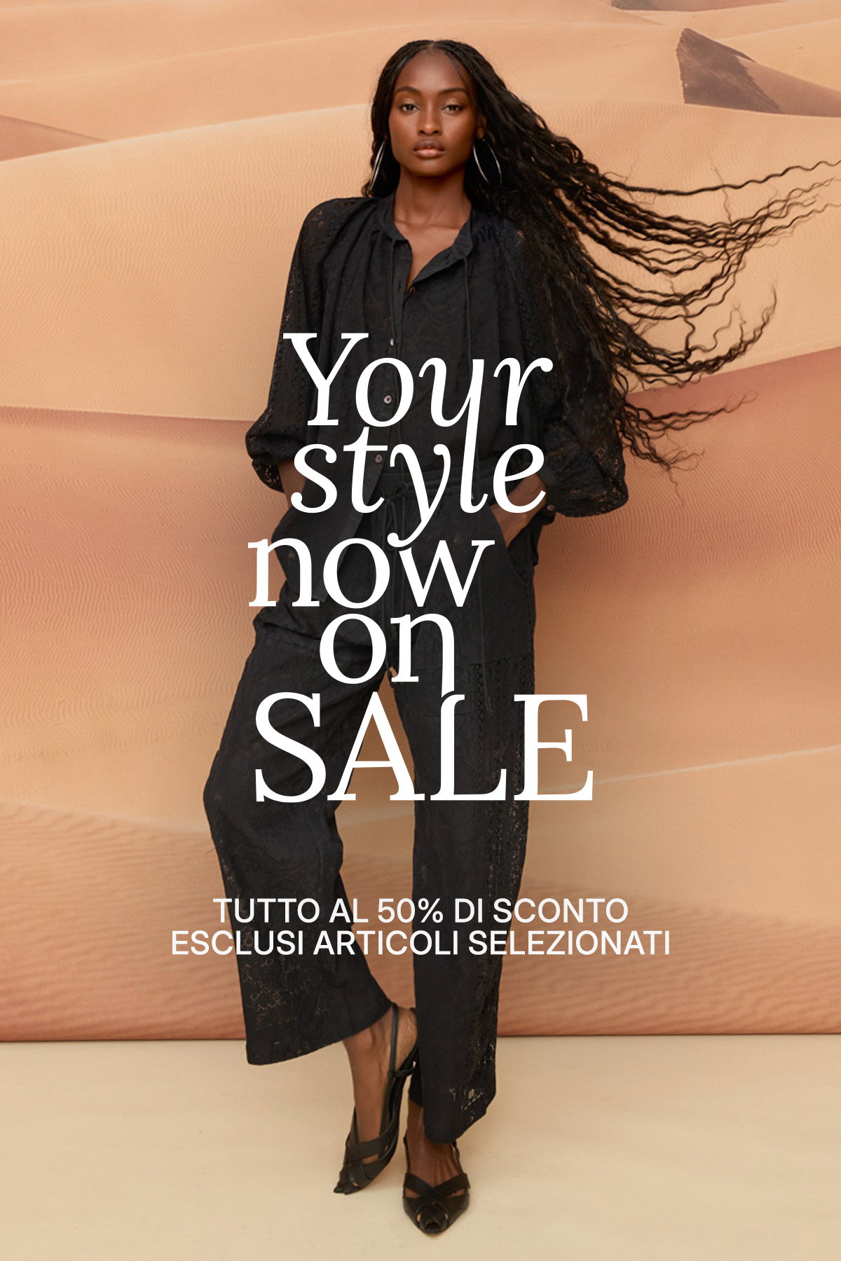 Woman model in a black outfit standing against a sand-dune backdrop with overlay text 'Your style now on SALE' promoting a sale