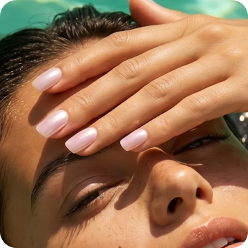 Close-up of a hand with Dashing Diva Drive You Crazy Glaze Effect nails resting on a woman's forehead as she reclines poolside.