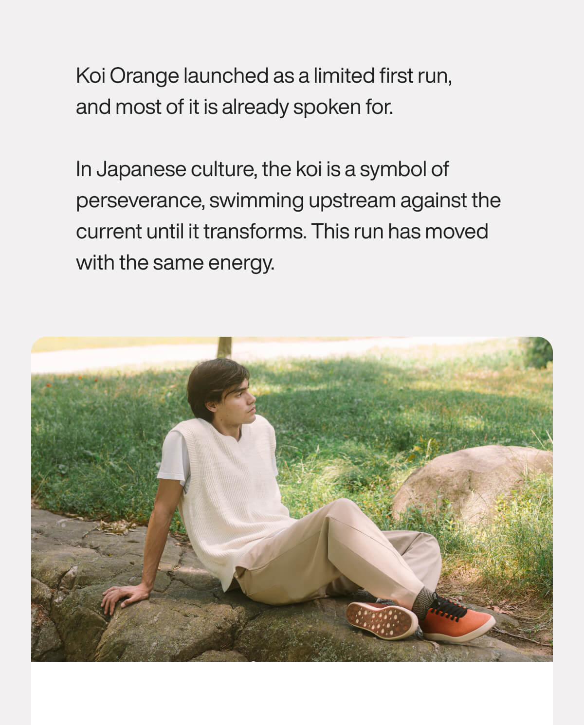 "Person in white vest and beige pants sits on a rock in a park, wearing orange shoes, symbolizing perseverance and energy."