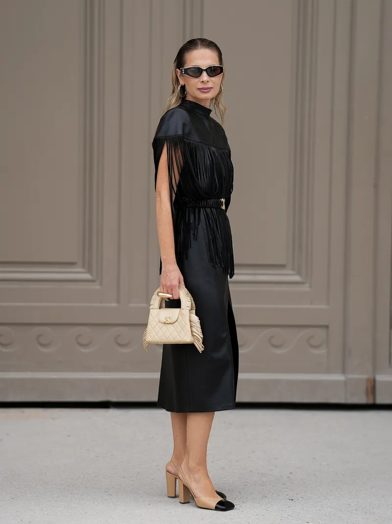 how to style ballerina heels - PARIS, FRANCE - JULY 7: Iryna Thater is seen wearing a black vegan leather midi dress with a front slit, styled with a black fringed leather cape, a black Chanel belt with a gold CC buckle, two tone beige and black Chanel slingback pumps, black rectangular Chanel sunglasses, silver hoop earrings from Chanel and carrying a beige quilted Chanel Nano top handle bag with fringe details and gold hardware during Day Two of Paris Fashion Week - Haute Couture Fall/Winter 2026/2027 at the Chanel Show on July 7, 2026 in Paris, France. (Photo by Moritz Scholz/Getty Images)