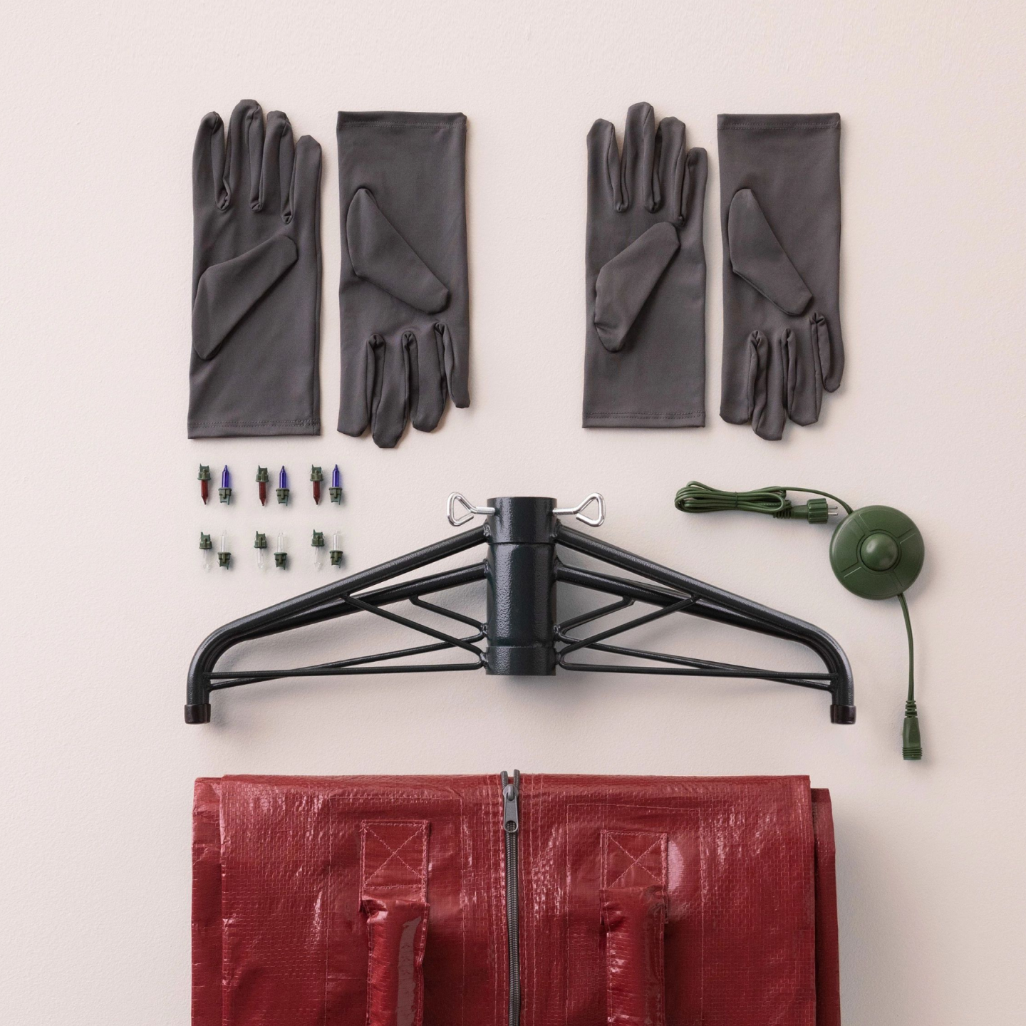 Christmas tree assembly kit with metal stand, gloves, and tools laid out on a surface.