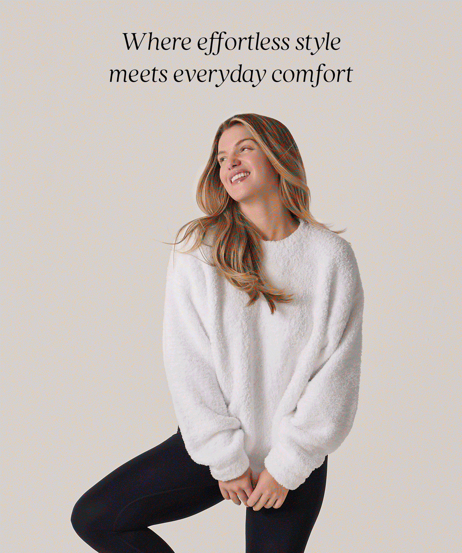 Smiling model wearing a white Kashwére crewneck pullover paired with black leggings. Where effortless style meets everyday comfort. A versatile layer designed with signature softness for year-round comfort, from cool summer evenings to cozy days at home.
