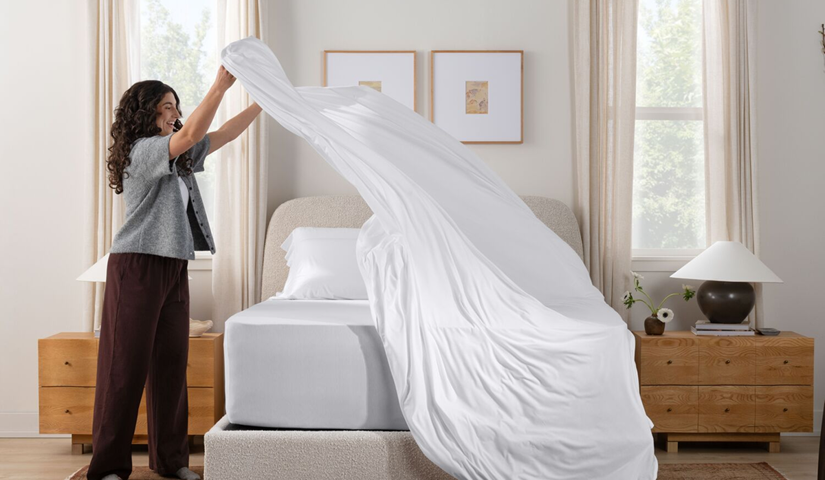 Woman putting bedsheet on bed