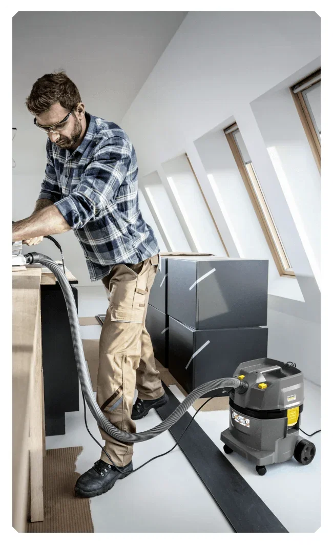 Man in flannel shirt using the Karcher Pro NT 600L Wet & Dry Vacuum Cleaner in an office space