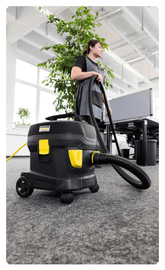 Woman standing in an office space with the Kärcher Pro T 11/1 Classic HEPA Re!Plast Dry Vacuum Cleaner