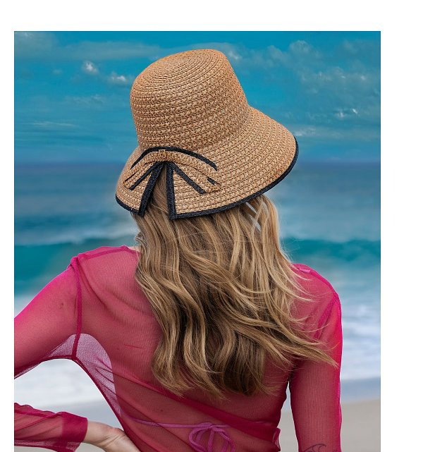A woman with long hair wearing a straw hat with a bow, and another woman smiling in a wide-brimmed straw hat.