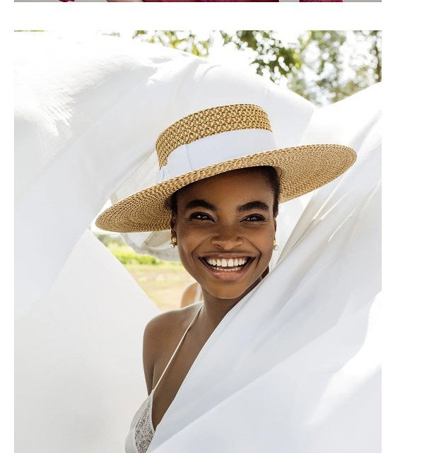 A woman with long hair wearing a straw hat with a bow, and another woman smiling in a wide-brimmed straw hat.