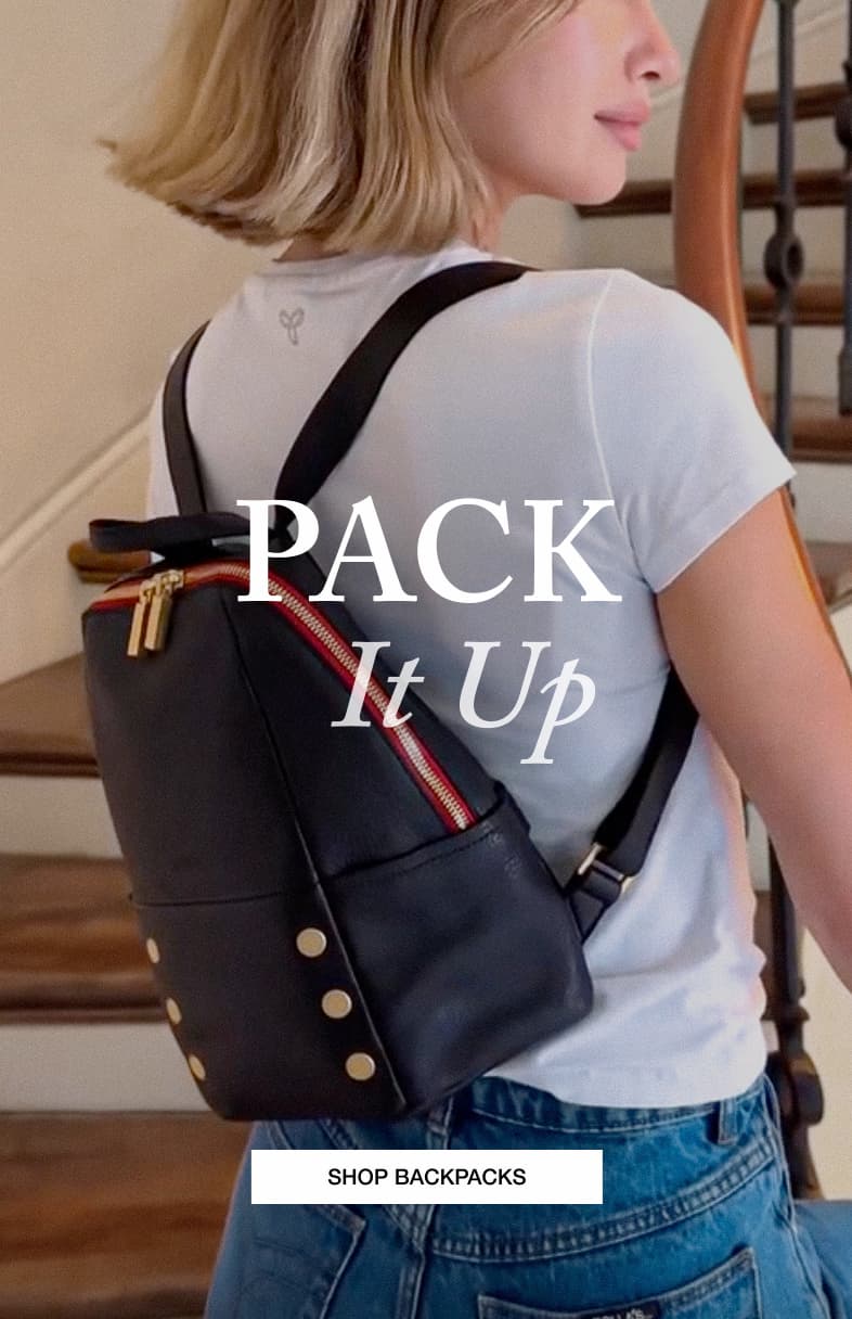 Model wearing the Hammitt Hunter Med backpack in Black/Brushed Gold Red Zip with headline "Pack It Up."