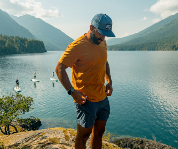 Shop summer travel staples. Model is wearing Men's Ferrosi Short 7 inches in the color Malachite, Men's Eclipse Sun T-Shirt in Sedona and Advocate Trucker Lo Pro Cap.  