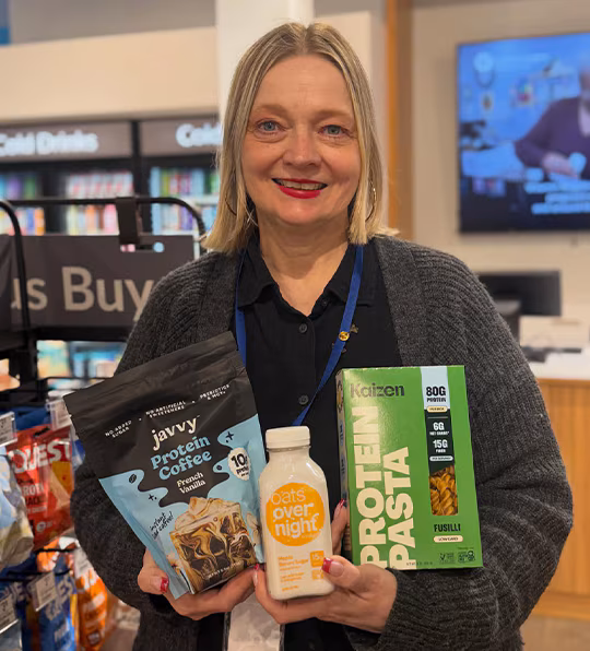Woman holding javvy Protein Coffee French Vanilla, oats over night and Protein Pasta items. Shop for these products
