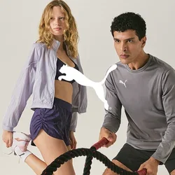 Un uomo usa le battle ropes in una posizione atletica e una donna si allunga la gamba, entrambi indossano abbigliamento sportivo su uno sfondo semplice.