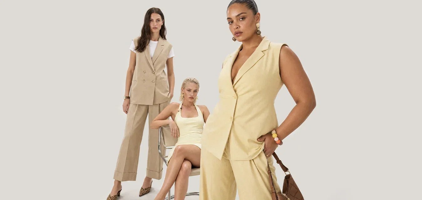 Tre donne che indossano abiti di moda beige e crema posano su uno sfondo chiaro e semplice con varie pose sicure di sé.