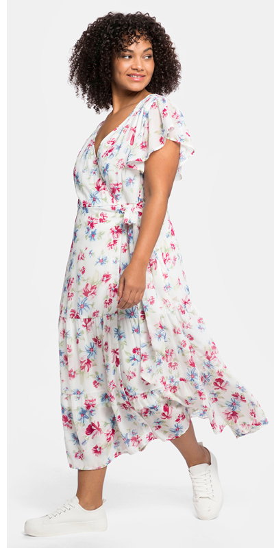 Ein Model trägt ein weiß bedrucktes Chiffonkleid mit Blumendruck, V-Ausschnitt in Wickeloptik