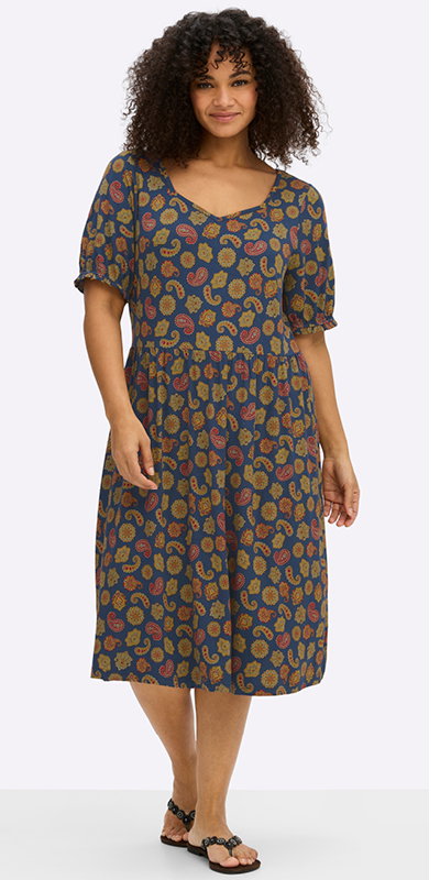 Ein Model trägt ein tiefblau-ozean-bedrucktes Jerseykleid mit Paisley-Alloverprint.