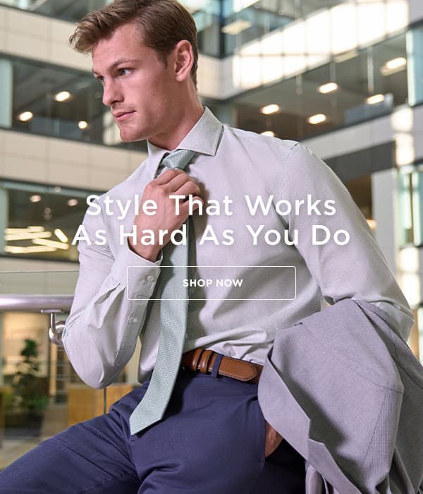 Man poses in a Haggar button up and dress pants, holding a sport coat