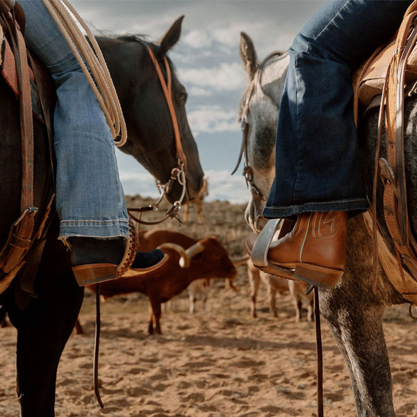 Two peoaple on horseback wearing Tony lama botos.