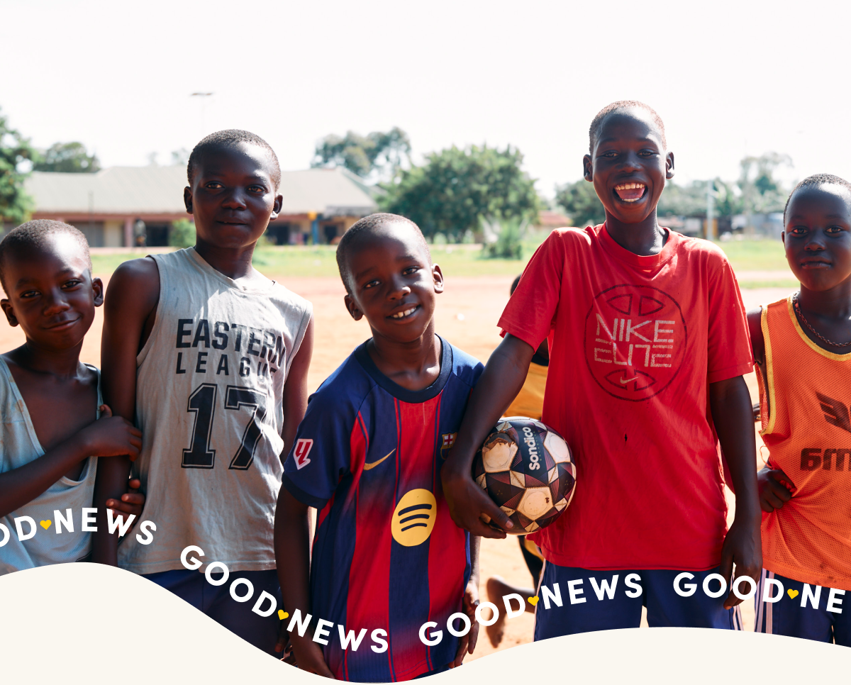 Young children smiling at the camera after a game of football.