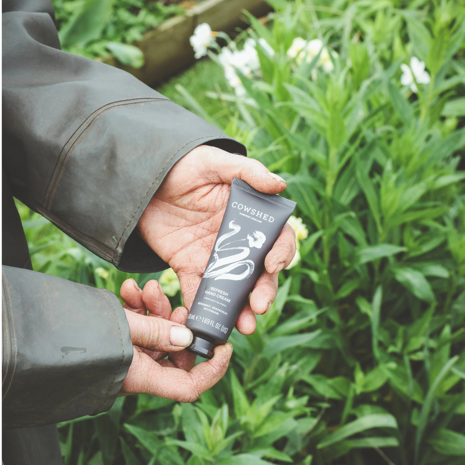 Refresh hand cream held in a British green garden