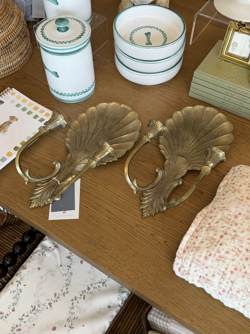 Vintage brass shell candle sconces on table.