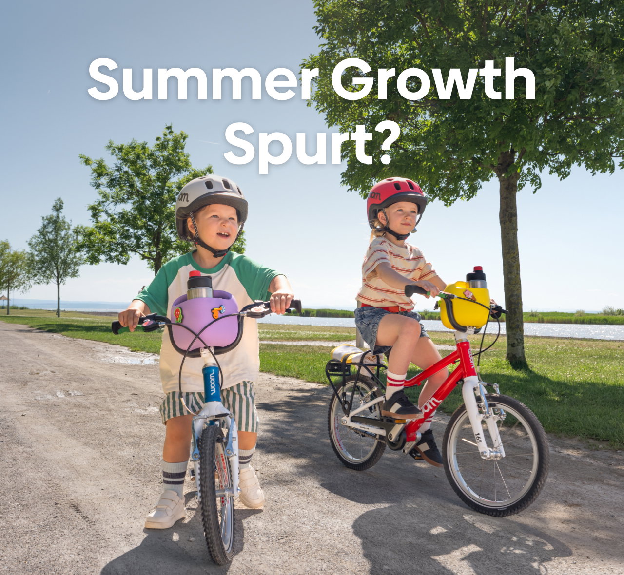 Two kids ride their woom GO bikes, complete with POP Baskets, READY Helmets, and POP ONs through a bayside park.