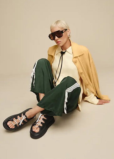 A model in a studio wearing UGG Sandals.