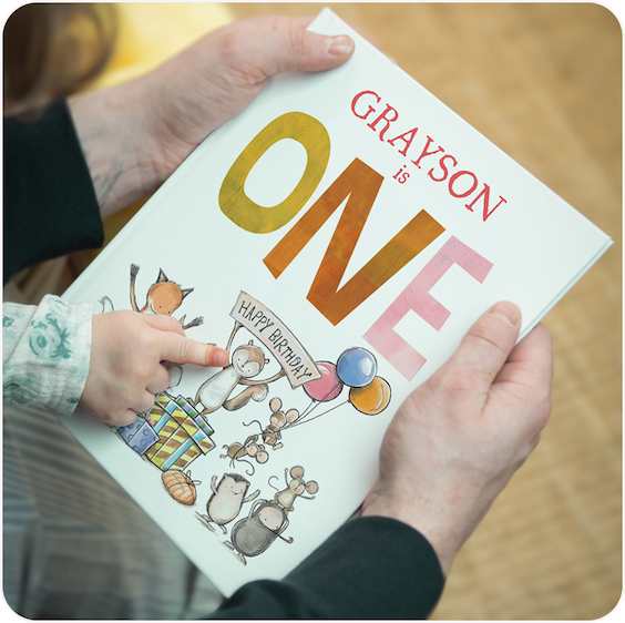 A personalised birthday story book with the name Grayson on the cover, held open to show the illustrated pages
