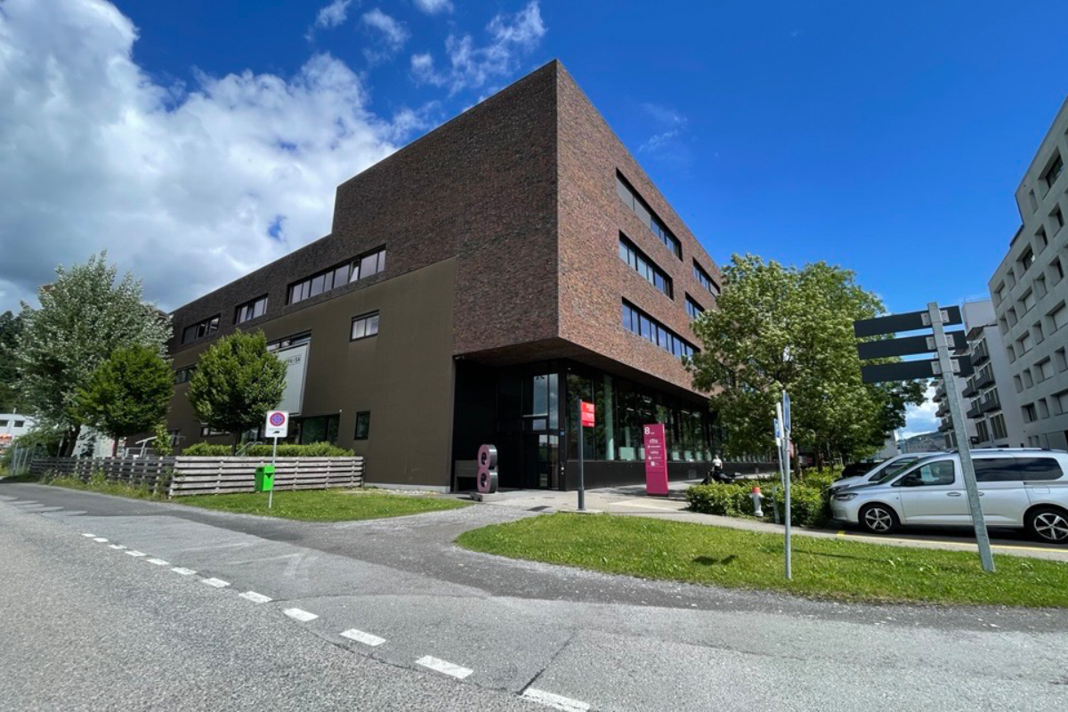 Moderne Gebäude mit klaren Linien, grosser Glasfront und angrenzenden Grünflächen.