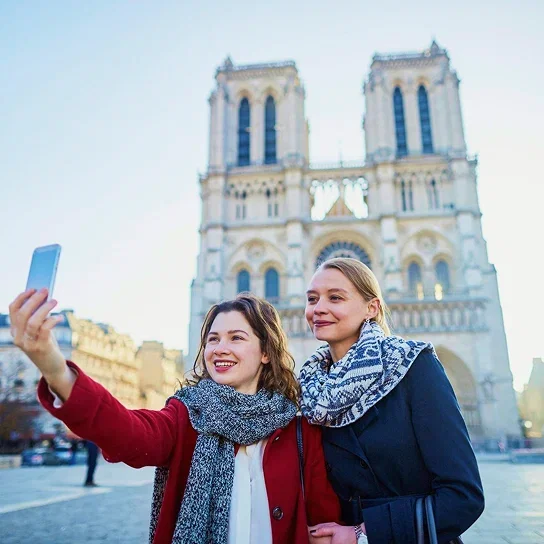 Two friends taking a selfie in front of Notre-Dame Cathedral in Paris.