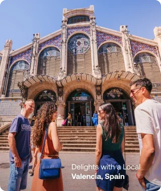 Travelers chatting with a local guide outside the ornate Mercado Central in Valencia, Spain.