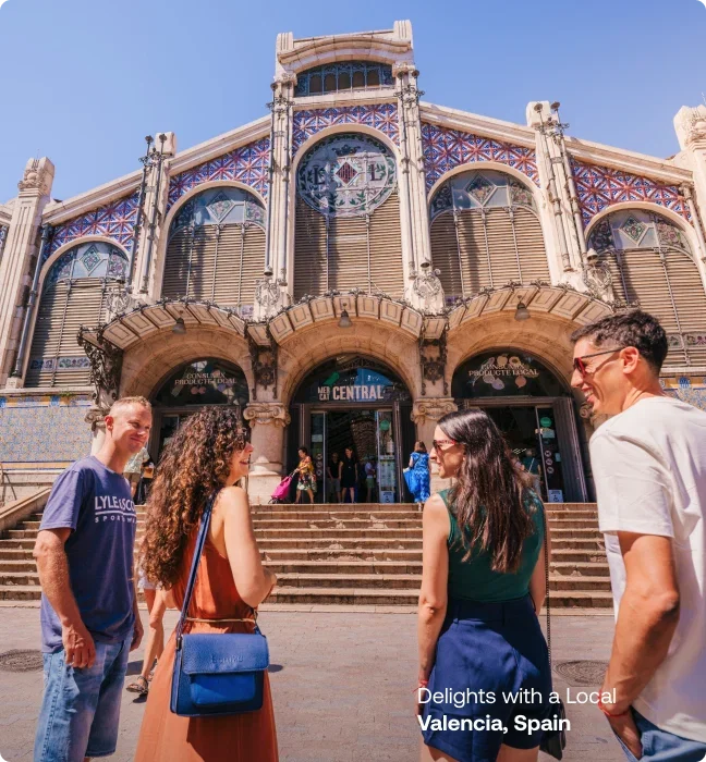 Travelers chatting with a local guide outside the ornate Mercado Central in Valencia, Spain.